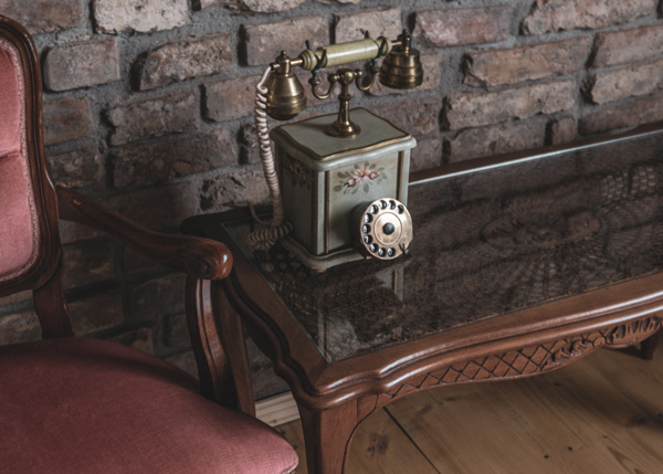antique phone on glass topped wooden coffee table against brick wall