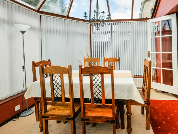 clear and simple dining table set up in glass conservatory of house