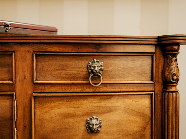 close up of brass lion drawer pull on antique chest of drawers